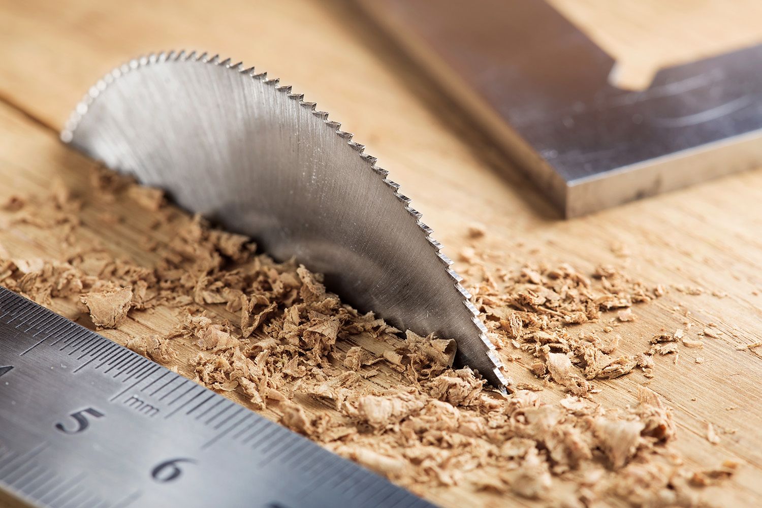Eine Sägeblatt und ein Lineal liegen auf einem Holztisch, bereit für präzise Schneidarbeiten.
